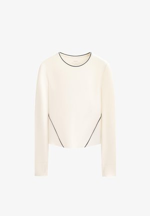 Haut crème à manches longues avec passepoils noirs, doté d'un col rond et d'un design sans coutures ; confectionné dans un tissu lisse légèrement brillant.