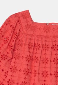 Korálový top s květinovou výšivkou, čtvercovým výstřihem a nadýchanými rukávy. Obsahuje výstřihy a nabírané detaily v pase.