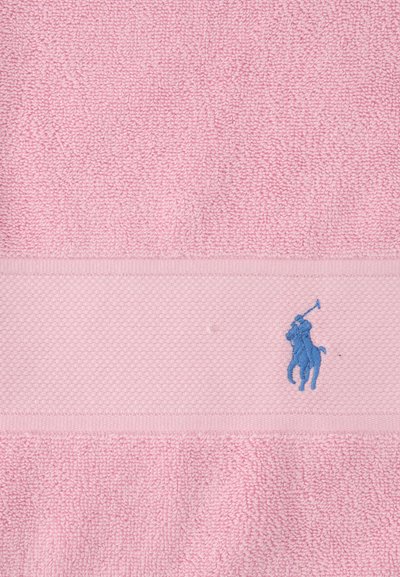 Ελαφρώς ροζ υφασμάτινη υφή με υφαντή ταινία που διαθέτει ένα μικρό μπλε κεντημένο σχέδιο αλόγου και ιππέα που κουνάει ένα μπαστούνι πόλο.