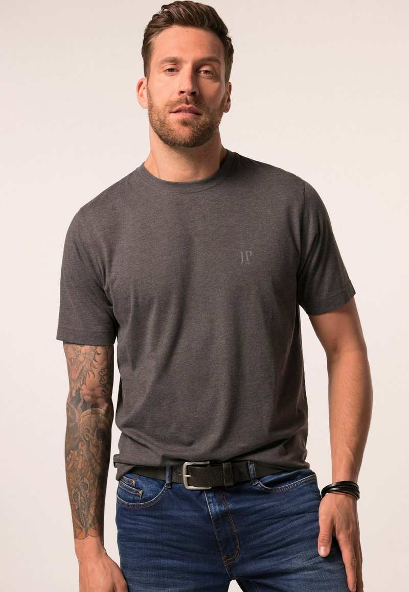 Mørkegrå kortærmet t-shirt med rund hals, med et diskret logo på brystet og en glat bomuldsstruktur, båret med blå jeans og et bælte.