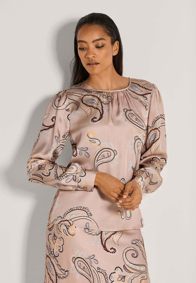 Langärmlige Bluse aus leichtem pinkfarbenem Satin mit Paisleymuster. Verfügt über einen gerafften Ausschnitt und aufwendige Stickereien in Blau- und Burgundtönen.