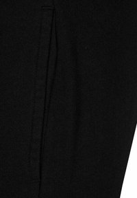 Pantalones de algodón negros con una textura suave, corte ajustado y detalle de bolsillo lateral, con costuras limpias y un diseño minimalista.