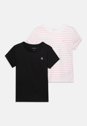 Δύο κοντομάνικα T-shirts Calvin Klein, ένα μαύρο με λευκό λογότυπο και ένα άσπρο με λεπτές κόκκινες ρίγες και κόκκινο λογότυπο, απλωμένα σε λευκό φόντο.