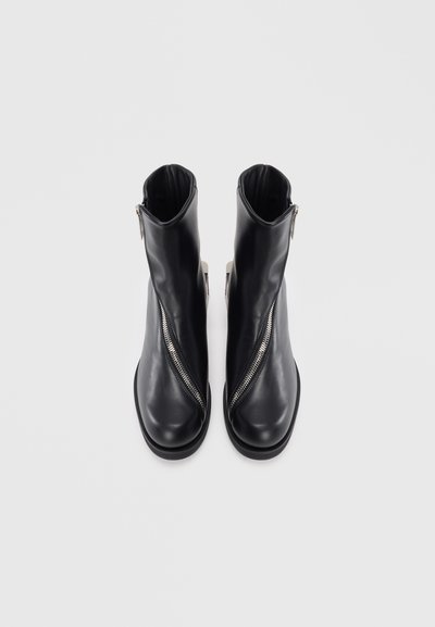 Black ankle boots made of smooth leather, featuring an asymmetrical zipper on the side, rounded toe, and a chunky sole.