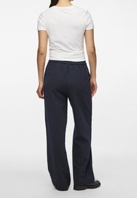 Marinrandiga vida byxor med elastisk midja, kombinerade med en tajt vit t-shirt, som visar en slät tygtextur.