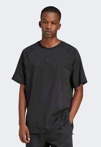Czarny t-shirt z raglanowymi rękawami, wykonany z miękkiej bawełny, z małym wytłoczonym logo na piersi. Luźny krój z okrągłym dekoltem.