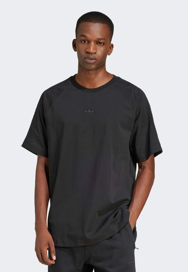 Czarny t-shirt z raglanowymi rękawami, wykonany z miękkiej bawełny, z małym wytłoczonym logo na piersi. Luźny krój z okrągłym dekoltem.