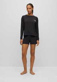 Zwart langemouwen top met "HUGO" logo en bijpassende shorts, gemaakt van zachte stof; ontspannen pasvorm en eenvoudige design zonder patronen.
