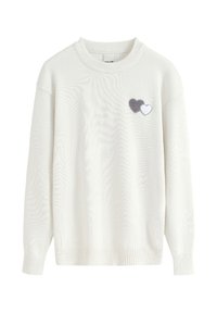 Pull en tricot blanc avec un col rond, comportant deux appliqués en feutre en gris et blanc sur le côté gauche. Tissu texturé.