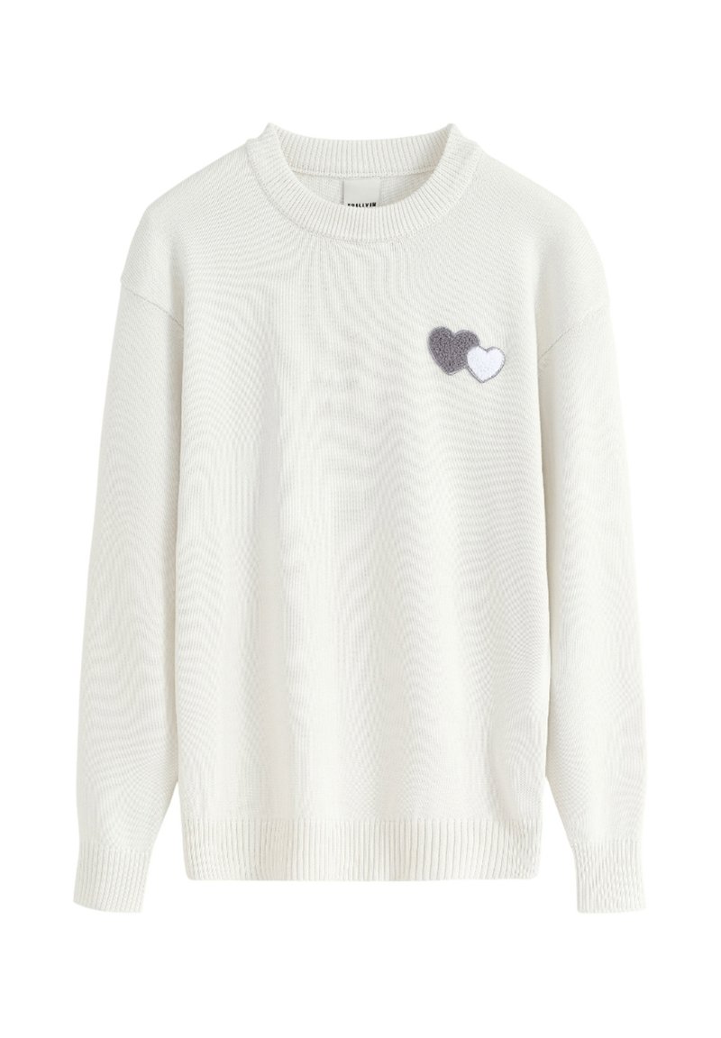 Pull en tricot blanc avec un col rond, comportant deux appliqués en feutre en gris et blanc sur le côté gauche. Tissu texturé.