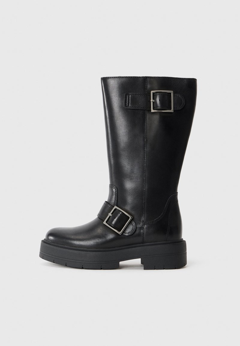 Botín de cuero negro hasta la rodilla con suela gruesa, presentando correas ajustables con hebillas en el tobillo y la pantorrilla. Textura suave con acabado pulido.