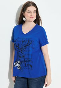 Modré bavlněné tričko s krátkými ohrnutými rukávy, véčkovým výstřihem a grafickým potiskem jelena a květin v černobílé barvě na spodním lemu.