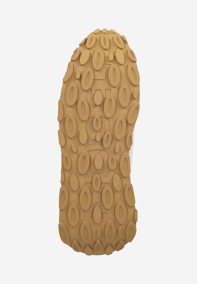 Rubber shoe sole featuring a textured pattern of oval and circular grips, in a tan color, with a flat profile and a central logo detail.