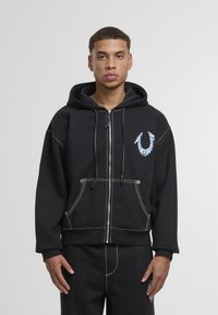 Černá mikina na zip s kapucí, se bílým prošitím, předními kapsami a barevným logem na hrudi. Hladký bavlněný materiál.