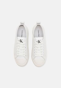 Baskets en cuir blanc avec bout rond, lacets plats et logo CK sur la languette. Texture lisse et semelle en caoutchouc contrastante. Design minimaliste.