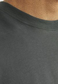 T-shirt grigio scuro con collo rotondo e colletto a costine. Texture liscia, dettagli di cucitura minimi e senza motivi o grafiche visibili.