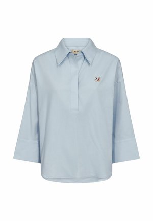 Lyseblå langærmet skjorte med brede manchetter, en bred krave og et lille multifarvet sommerfuglepatch på venstre bryst.