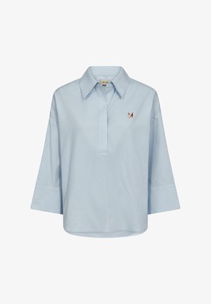 Světle modrá košile s dlouhým rukávem, širokými manžetami, širokým límcem a malou vícebarevnou nášivkou motýla na levé straně hrudi.