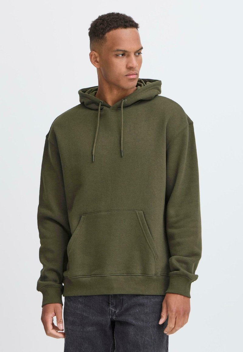 Donkergroen hoodie, katoenmix, kangoeroezak, capuchon met trekkoord, geribbelde manchetten, ontspannen pasvorm, gedragen met donkere jeans.