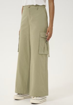 Cargo broek in licht olijf groen, gemaakt van stevig materiaal met brede pijpen, zijzakken en een knoopsluiting bij de taille.