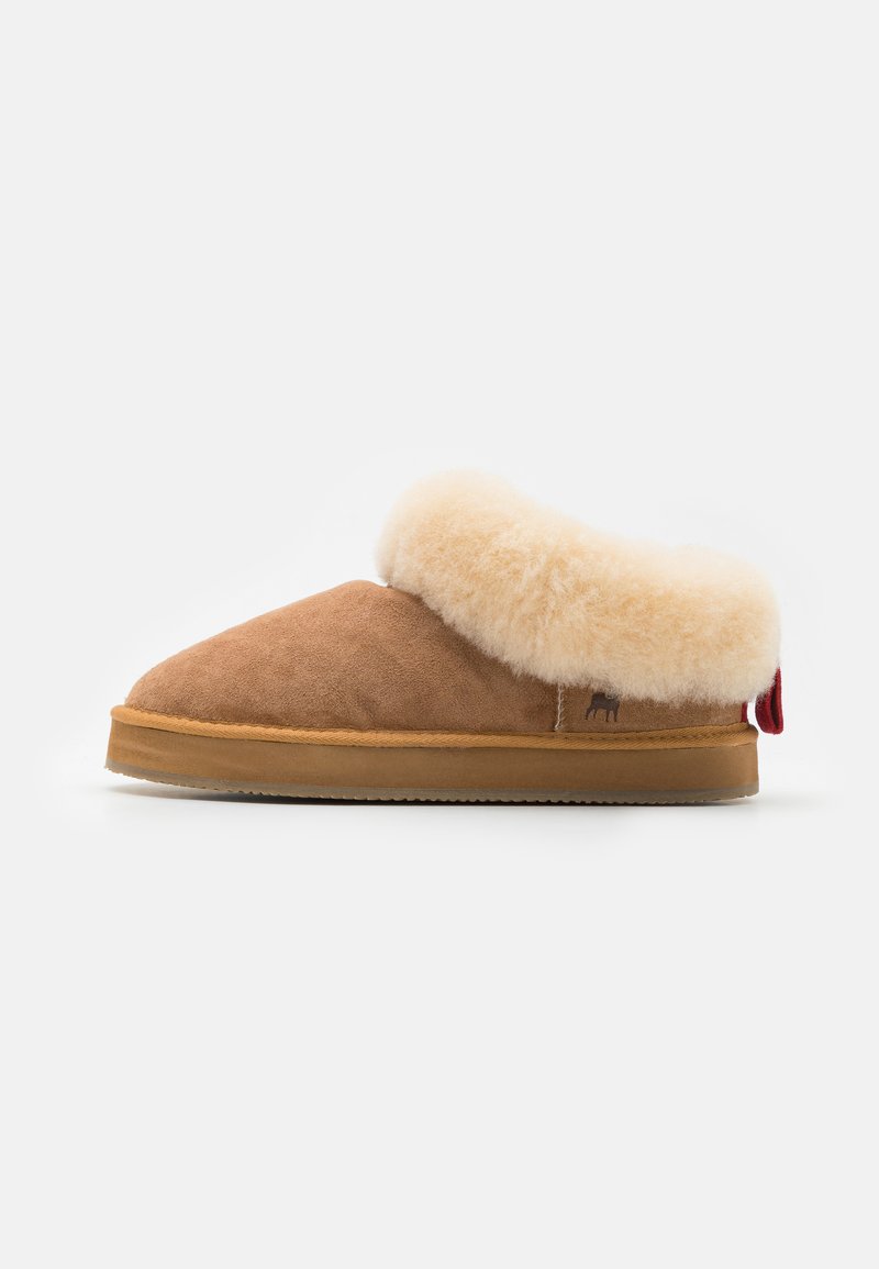 Chaussure en daim brun avec un revers en shearling crème, bout arrondi, semelle en caoutchouc tan et accent rouge à l'arrière. Texture douce et design simple.