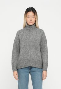 Hallgray turtleneck-sviiter ribaste tekstuuriga, millel on langenud õlad ja mugav lõige, koos helesiniste teksadega.
