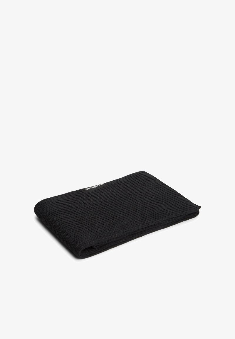 Écharpe en tricot côtelé noire pliée à plat avec une petite étiquette blanche "Tommy Jeans" près du bord sur un fond blanc.