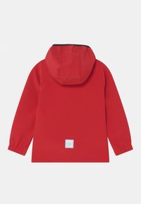 Veste imperméable rouge avec une capuche, des poignets élastiques et une étiquette de logo de marque blanche dans le dos. Texture lisse et design moderne.