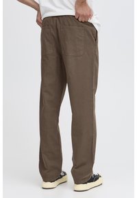 Pantaloni marroni leggeri in cotone con vestibilità comoda, vita elastica, due tasche posteriori e dettagli di cuciture visibili.