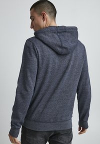 Felpa con cappuccio di un blu navy scuro, realizzata in un tessuto testurizzato e mélange; presenta un cappuccio con coulisse, polsini a coste e una vestibilità comoda.