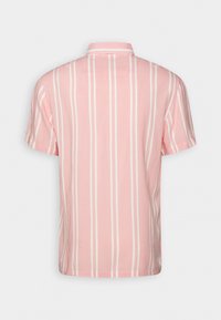 Chemise rose à manches courtes avec des rayures blanches verticales, vue de dos avec un petit col sur un fond uni.