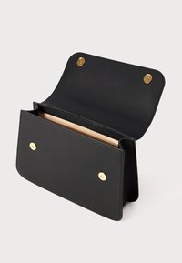 Black leather handbag with a structured design, featuring a smooth texture, two gold-tone snap closures, and an open interior.