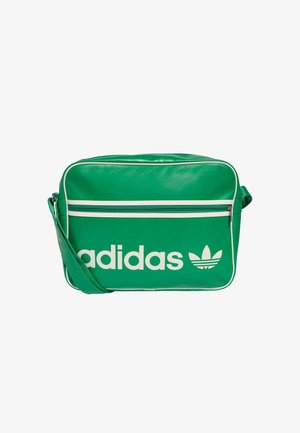 Grønn syntetisk crossover-veske med hvit "adidas"-logo, glidelåslomme foran og kontrastfarget hvit piping. Justerbar skulderreim.