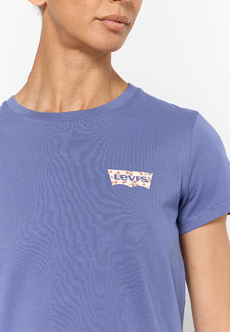 Krótki rękaw, fioletowy t-shirt wykonany z bawełny, z wielokolorową naszywką logo Levi's na lewej piersi. Gładka tekstura i okrągły dekolt.