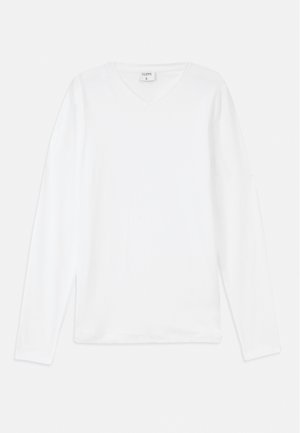 Camiseta blanca de manga larga con cuello en V, hecha de material suave, que presenta un corte holgado y aberturas laterales para mayor comodidad.
