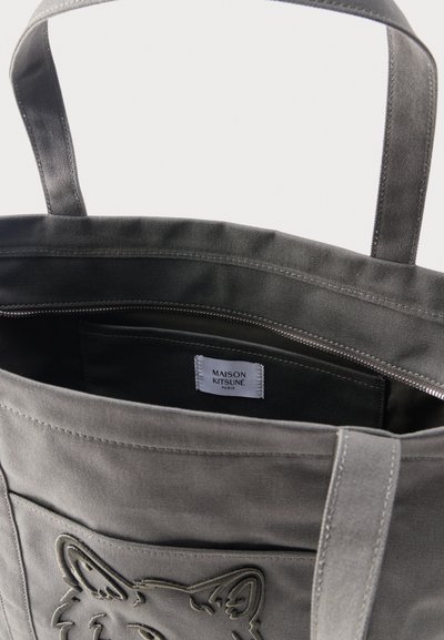 Γκρι τσάντα tote από καμβά με κεντητό σχέδιο αλεπούς, κλείσιμο με φερμουάρ και ετικέτα «Maison Kitsuné Paris» στην εσωτερική τσέπη.