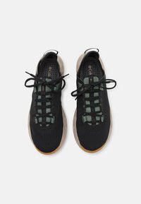 Sorte sneakers med en struktureret mesh-overdel, grønne snørebånd og en gummisål. Rund tå og afslappet snørebåndsdesign med bløde detaljer.
