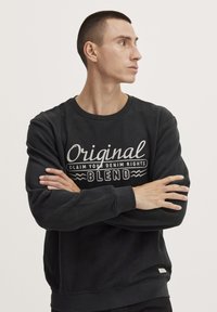 Černá mikina s kulatým výstřihem, elastickými manžetami a vyšitým textem "Original Blend" na hrudi. Měkká textilie.