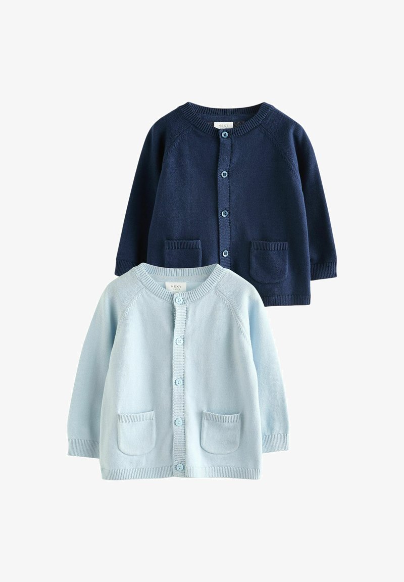 Deux cardigans pour bébé, un bleu marine et un bleu clair, tous deux avec des boutons et de petites poches avant, posés à plat sur un fond blanc.