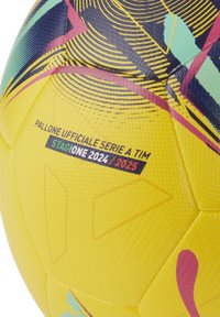 Palla da calcio gialla con superficie texturizzata e motivi colorati a spirale in blu, rosso e verde. Contrassegnata per la stagione 2024/2025.