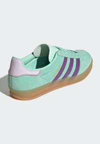 Mintgrön mockaskor med lila ränder, en ljuslila hälkappa och en genomskinlig gummisula. Har en texturerad tunga.