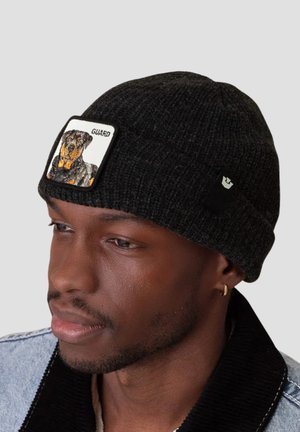 Black knitted beanie with a rectangular patch featuring a Rottweiler illustration and the word "GUARD." Textured fabric and snug fit.