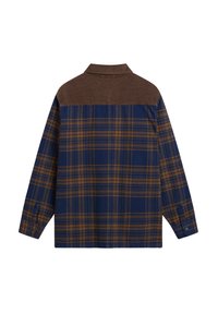 Rutiga flanellskjortor i blå och bruna toner, med en brun kordflorskrage, långa ärmar och knäppningar vid ärmsluten. Rik textur genom hela skjortan.