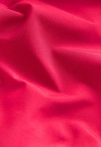 Tela roja lisa con pliegues suaves y textura sutil en vista de cerca.