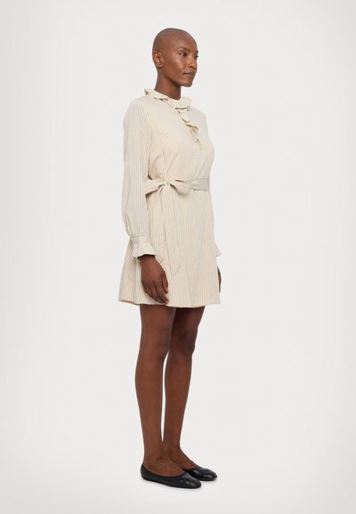 Beige striped dress with long sleeves, ruffled collar, and a belted waist. Features a relaxed fit and a hem that falls above the knee.