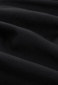 Črno blago z gladko teksturo, ki ima valovite gube. Material deluje mehak in prožen, z globoko, enakomerno črno barvo.