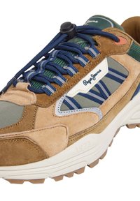 Sneaker in suede marrone e grigio con linguetta in rete, lacci blu navy, suola in gomma e dettagli bianchi che presentano un logo e l'anno '1973' impresso.