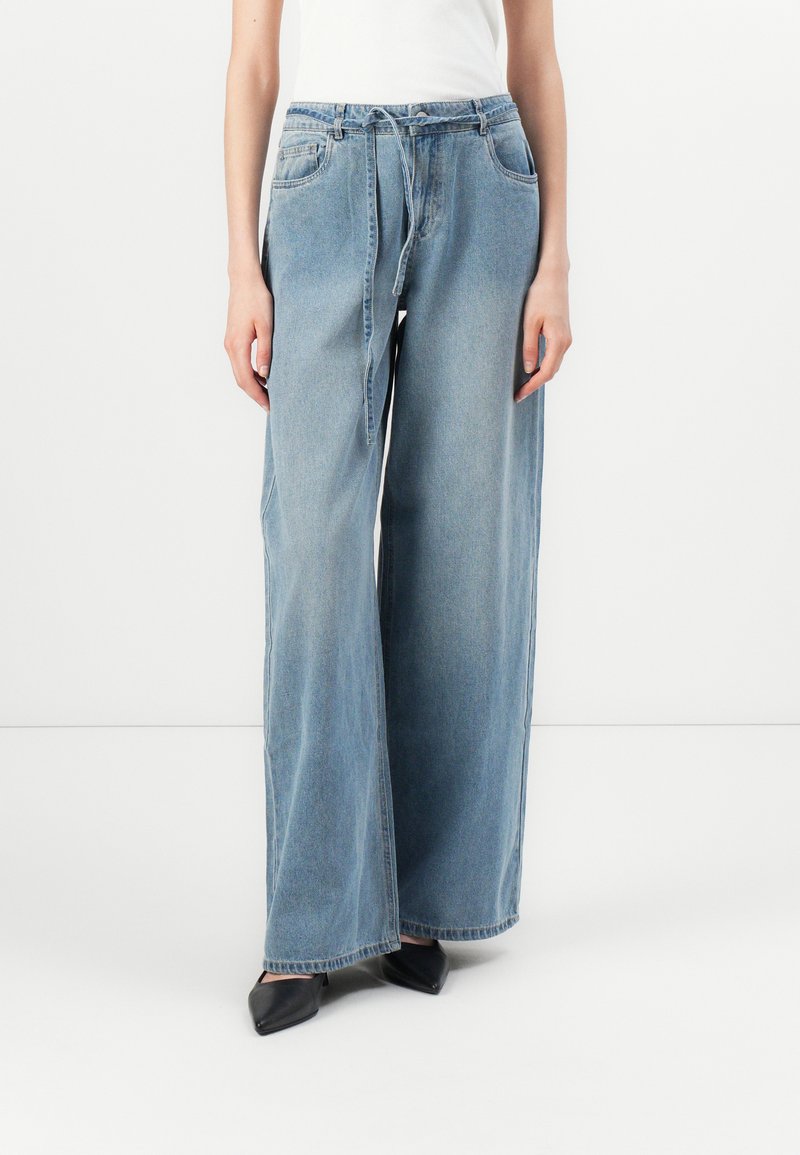 Ανοιχτό μπλε φαρδιά τζιν παντελόνια από τζιν ύφασμα, με ψηλή μέση, θήκες για ζώνη και μπροστινές τσέπες. Λεπτή υφή και χωρίς ορατά σχέδια.