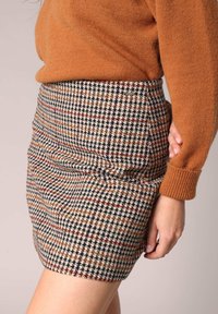 Houndstooth rok in tinten van bruin, crème en marineblauw; heeft een aansluitende Silhouet en subtiele zijkanten plooien. Geaccentueerd met een logo label.