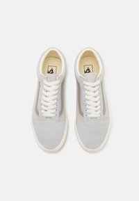 Baskets basses en suede gris avec des lacets blancs, une bande latérale de contraste et un empiècement en cuir texturé à l'avant. Design minimaliste avec une finition lisse.